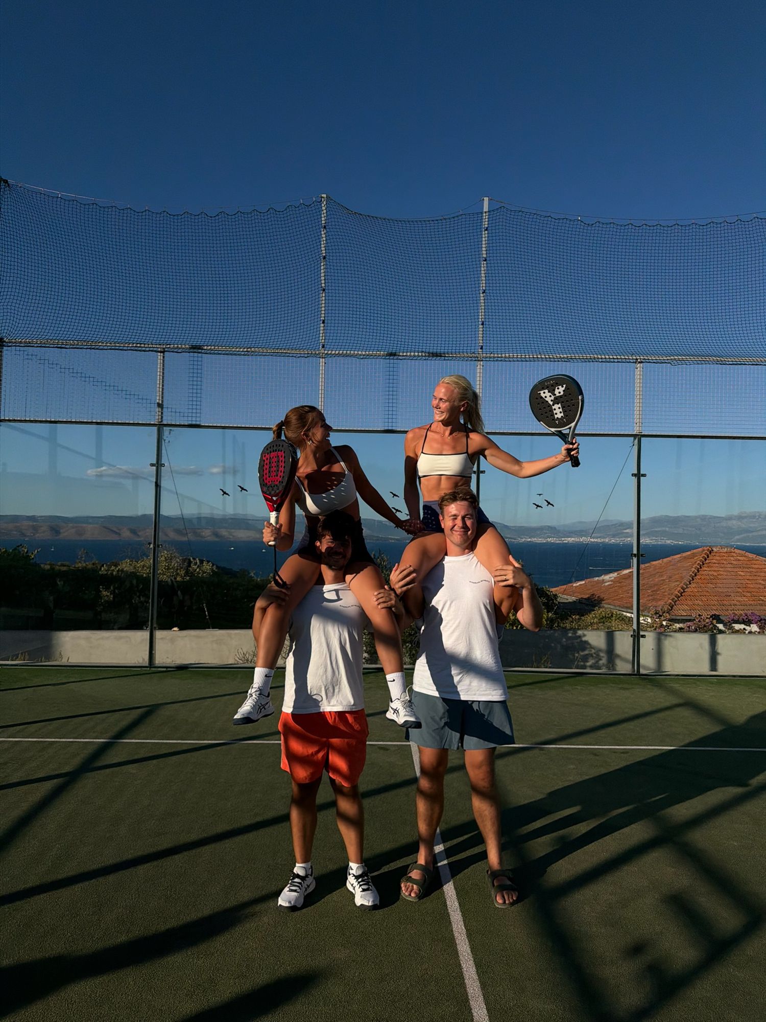 Friends on each other's shoulders on court, rackets raised